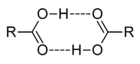 This image illustrates how two carboxylic acids, C O O H, can associate through mutual hydrogen bonds. The hydroxyl portion O H of each molecule forms a hydrogen bond to the carbonyl portion C O of the other.