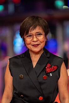 An image of a woman wearing a black sleeveless top and smiling to the camera