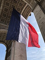 French flag suspended from the vault of the great archway.