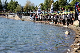 Photo en couleur, on voit des triathlètes en combinaison qui attendent le départ.