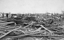 Black-and-white photograph highlighting wreckage and wooden boards