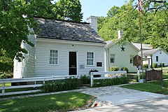 White clapboard house and outbuildings behind a white fence