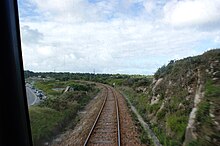 vue prise de l'avant du train. Au centre la voie et à gauche la route.