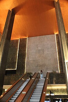 View of the International Building's lobby, looking up the escalators toward the mezzanine