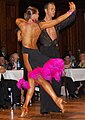 Image 28Latin dancers in their costumes. The woman is wearing backless dress with deep slits on its lower portion, while the man is wearing a shirt with top buttons open. (from Fashion)