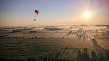 Paramotor flies over a thin layer of light fog.