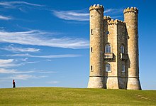 Yellow stone tower with two circular turrets which run the height of the building.