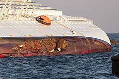 Ship lying on the side, hull gash with boulder is seen below exposed waterline of ship