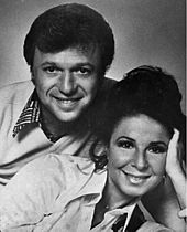 A dark-haired man and a dark-haired woman, both smiling broadly