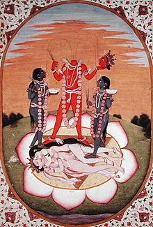 A decapitated, red-complexioned, nude woman stands on a copulating couple inside a large lotus. She holds her severed head and a scissor-like weapon. Three streams of blood from her neck feed her head and two blue-coloured nude women holding a scissor-like object and a skull-cup, who flank her. All three stand above a copulating couple.