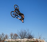 Un cycliste à plusieurs mètres en l'air et la tête en bas.