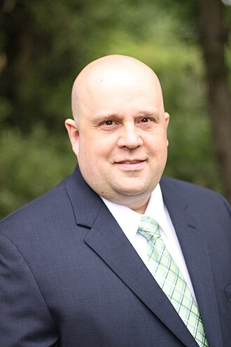 John Pestinger in a blue suit with a green tie and white shirt