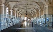 Vue de la galerie en enfilade bordée de vitrines présentant les pièces.