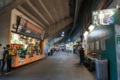 A shot of the concourse showing a vendor of A's merchandise, a bathroom sign, and entrances to the stadium seating