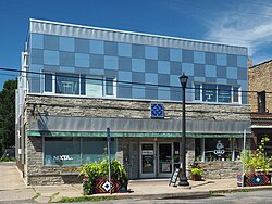 A small two-story building fronting the sidewalk, with a recessed center entry