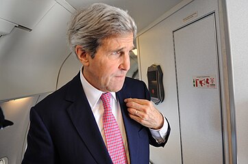 John Kerry adjust his American flag pin before arriving in Vietnam, 2012.