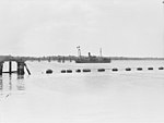 Anti-submarine boom gate in open position (foreground) and permanently anchored ship "HMAS Kinchela" (background). 1943. [gallery 13]