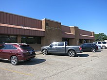 Color photo shows vehicles parked in front of a brick building named Alvin Post Office.