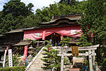 Building at the top of a flight of modern stairs with undulating Chinese style gable at the front. The lower part is covered by a red cloth which is hung from the eaves of the roof.