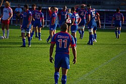 Un joueur est de dos au premier plan devant le reste de l'équipe au second plan