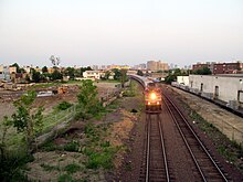 A train passing a cleared parcel in an urban area