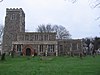 A rubble-stone church with a slate roof. On the west end is a castellated tower, with lower nave and chancel to the east. A red brick porch fronts the building