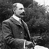 Black and white photograph of a seated man with a mustache