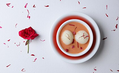 Rasgulla com rabri, um prato festivo que combina os sabores de duas sobremesas tradicionais, rasgulla e rabri, ambas feitas à base de leite. Açafrão e rosa são adicionados para acentuar o sabor e o aroma. Rasgulla (literalmente “bola cheia de xarope”) é uma sobremesa de xarope popular na parte oriental do sul da Ásia. É feito de bolinhos de massa de chhena em forma de bola, cozidos em calda de açúcar. Isso é feito até que a calda permeie os bolinhos. Rabri é um prato doce à base de leite condensado. Jagra, especiarias e nozes são adicionados a ele para dar sabor. É refrigerado e servido como sobremesa. (definição 3 114 × 1 900)