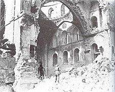 Black & white image of a lone soldier gazing at synagogue interior through a destroyed side wall