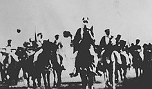 A black-and-white photograph of men riding horses