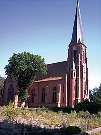 Die neugotische Maria-Magdalenen-Kirche (evangelisch) in E.-Süd im alten Dorfkern. Der versteppte Platz im Vordergrund ist die Verfüllung des ehemaligen Dorfteiches aus den 1950er/1960er Jahren, der damals auch als Löschwasserteich diente (Aufnahme Juni 2008).