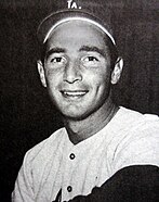 A baseball player with a Dodgers cap, smiling and looking ahead