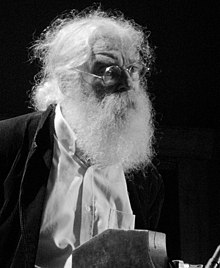 Black and white photograph of a man with a long beard and circular glasses