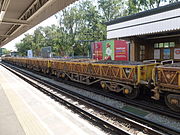 An engineering train composed of 'SB' wagons passes through Ruislip tube station westbound on tracks shared by the Metropolitan and Piccadilly lines in July 2011. The cargo appeared to be old ballast.