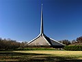 Hexagonal gray-roofed building with a spire about twice as tall as the building itself