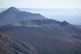 Vue depuis le mont Karakuni du mont Shinmoe (premier plan) et du Takachihonomine (dernier plan) en janvier 2017 ; sous le cratère du mont Shinmohe sont visibles les fissures volcaniques sur le flanc ouest.