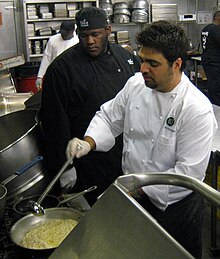 Albisu stirs a pot of risotto while another person looks on