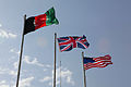Afghan, British and US flags on poles during a ceremony in Helmand Province (2010)