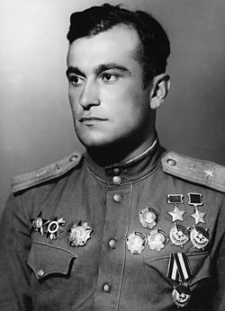 1945 formal postwar portrait of a handsome young major (Amet-khan Sultan) in parade dress of the Soviet Air Forces looking off into the distance. He is seen wearing his two hero of the Soviet Union medals, three orders of Lenin and three orders of the red banner on one side of his chest (right side in photo, left in life) and his Order of the Red Star, Order of the Patriotic War, and Order of Aleksander Nevsky on the other side.