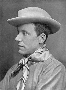 A profile photograph of a thin, clean-shaven man in his mid-thirties. His facial features are somewhat angular. He wears a brimmed hat and neckerchief.
