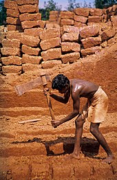 A man is cutting laterite into brickstones in Angadipuram, India.