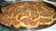 Sfiha, also known as Arab pizza, is a dish originating from the Arabian Peninsula and Levant, introduced in Brazil by Levantine immigrants.
