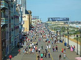 People walking along a wide pathway near the ocean on a sunny day