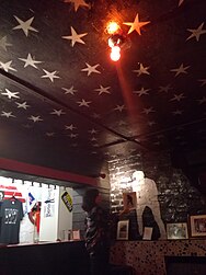 A room with stars painted on the ceiling and a silhouette painted on the wall. Framed photos are hung up all around the room.