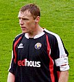 A man wearing a black, red and white football shirt.