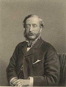 A middle-aged man, with sideburns and moustache, wearing a dark suit with a wing-collared shirt and cravat; a monocle hangs from a chain around his neck