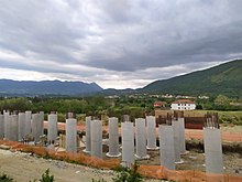 The picture shows a construction site with concrete pillars