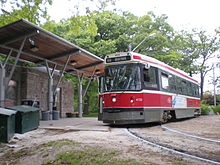 large transport vehicle on rails at station with trees behind