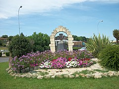 Premier rond-point à l'entrée de Saint-Girons joliment fleuri avec une cloche en bronze, emblème de la ville.