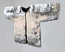 The picture show´s a big shirt composed of thin splinters display glass by breaking it with pliers; she then arranges these shards on top of and next to each other before bonding them invisibly